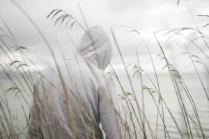 a-lonely-sad-person-from-behind-with-a-hoodie-sitting-near-the-sea-thinking-about-life-300x200