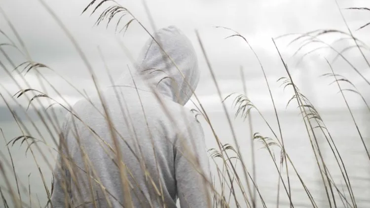 a-lonely-sad-person-from-behind-with-a-hoodie-sitting-near-the-sea-thinking-about-life-750x422